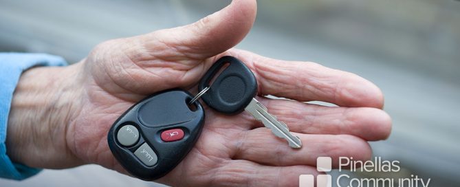 Close up of older adult’s hand offering car key.