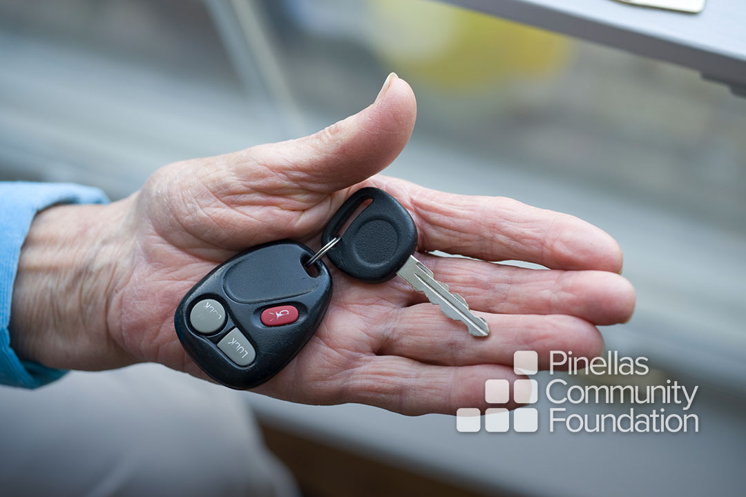Close up of older adult’s hand offering car key.