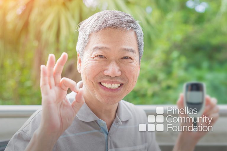 Diabetic man holding glucometer signs OK with hand.