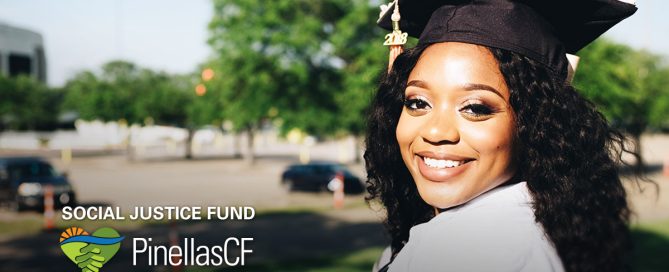 A Black college graduate smiles while wearing cap and gown.