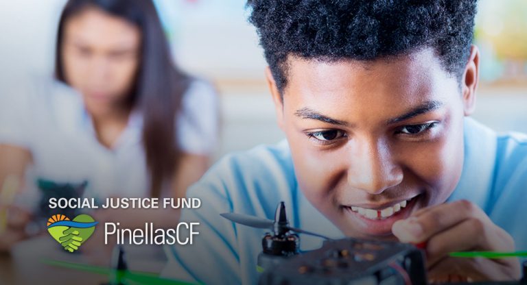 A teenage Black boy smiles as he works on a drone in the YDI Drone Club supported by PCF's Social Justice Fund.