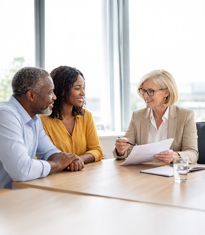 A couple reviewing planning documents with their advisor across a conference table.