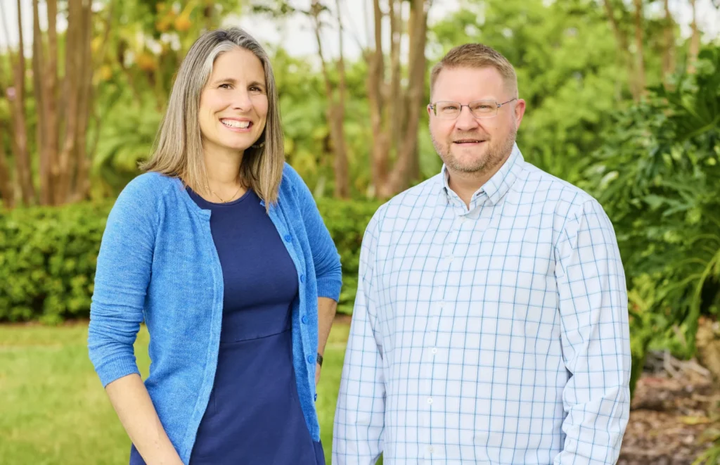 Meg Lokey and Duggan Cooley of Pinellas Community Foundation, standing outdoors among tropical plants.