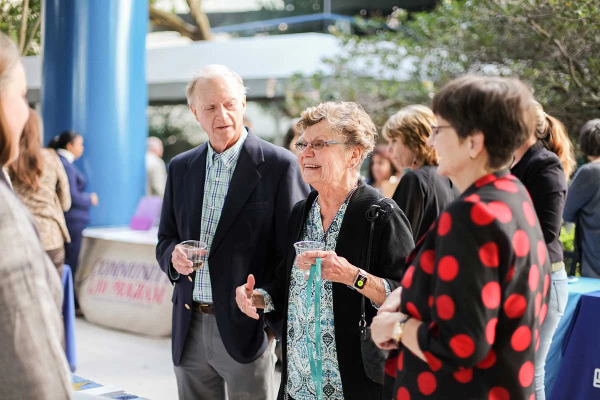 Guests holding drinks chat together at an outdoor Pinellas Community Foundation gathering.